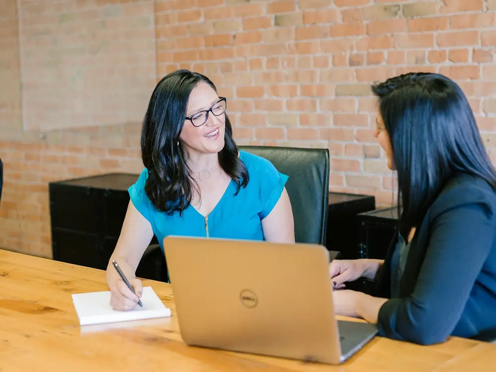 Two women chatting over a laptop at a friendly business meeting